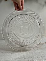 Front view clear pressed glass cake plate showing starburst pattern and scalloped edge