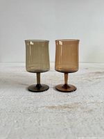 Front view of both smoky stemmed glasses, gray and brown