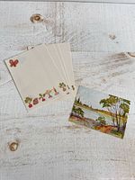 Four decorative note sheets and one landscape card on light wood surface