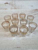 Group of ten shot glasses showing gold rims and starburst bases
