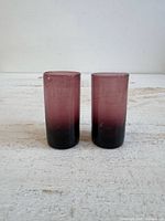 Two purple gradient glass shot glasses standing side by side