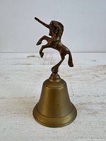 Full view of brass bell with rearing unicorn handle