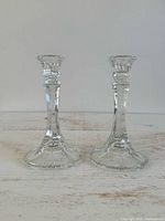 pair of clear glass candlestick holders standing upright
