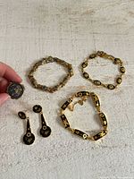 Group shot of locket, three bracelets and pair of earrings