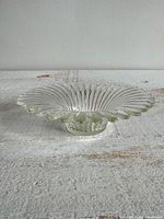 side profile of clear glass flower candle holder showing pedestal and petal rim