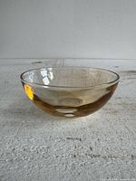 Side profile of small light orange luster glass bowl on white surface