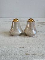 Front view of both shakers showing iridescent bodies and gold tops