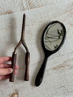 Curling tongs and hand mirror side by side for size and material overview