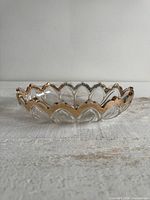 Side profile showing scalloped gold edge and clear glass body