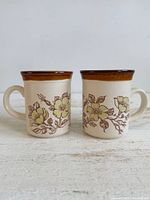 Front view of both mugs showing floral pattern and brown rims