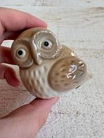 Front angled view of owl figurine held in hand for scale