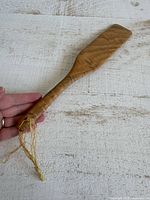 Overall view of full wooden spatula showing length and hanging string