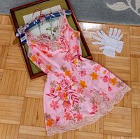 Full view of floral nylon chemise laid flat showing print, lace hem and frame props