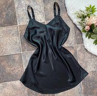 Front view of black satin slip dress laid flat