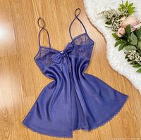 Front view of slate blue silk lace babydoll laid flat on wood floor with floral prop