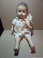 Full view of 22-inch composition baby doll seated, showing outfit and limbs