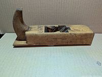 Side view of wooden plane showing curved sole and missing blade