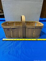 Side view of wooden bushel basket with measuring tape showing length