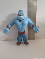 Front view of blue Genie bendable figure with ruler for scale