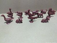 All fifteen brown plastic farm animal figures arranged on plain background