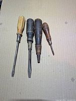 Four wood handled screwdrivers lined up showing varying sizes and condition