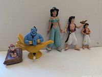 Five figures including Genie on lamp, Jasmine, two Aladdin variants, Abu on carpet
