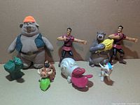 Group shot of eleven Disney fast-food premium figures including plush pig, two Gaston, Baloo, gargoyle, Pumbaa, slug, snail, Mushu, Pegasus