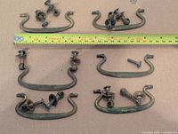 Six brass drawer pulls with tape measure showing width and accompanying bolts