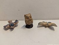 Three miniature Wade Whimsies figurines displayed side by side: blue bird, owl, butterfly