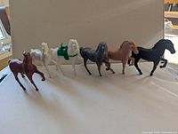Six plastic horse figurines lined up side view