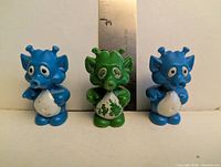 Front view of three alien figures with ruler for scale