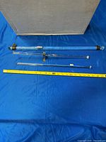 Three clear glass towel rods laid next to measuring tape showing approx 24 in and 18 in lengths