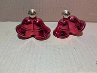 Front view of two metallic red bell bottles with gold tops