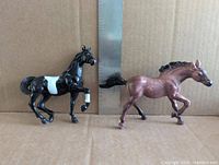 Both plastic horse figurines side by side with ruler for scale