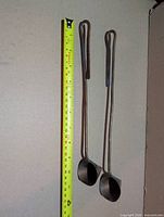 Front view of both copper candle snuffers beside tape measure