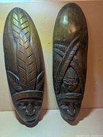 Both elongated wooden masks side by side