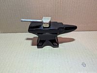 Side view of anvil-shaped brown glass bottle with hammer cap