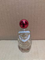 Front view of clear Santa-shaped perfume bottle with red cap
