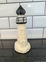 Front view of cream lighthouse decanter showing door detail and black top