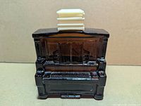 Front view of brown glass piano-form aftershave bottle showing detailed keyboard and white cap