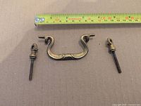 Drawer pull handle with two bolts and measuring tape for scale