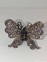 Front view showing filigree butterfly wings and purple rhinestones