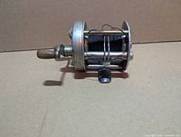 Side view of reel showing frame, black line and handle