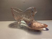 Left side profile of rose pink pressed glass cat head slipper showing Daisy & Button pattern and heel.