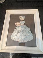 Front view of framed ribbon paper doll art showing full design