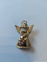 Front view of gold tone angel brooch with enamel details