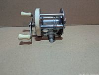 Side view showing full reel with ivory-tone handles and side plate