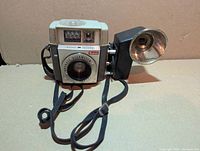Front view of Kodak Brownie Starmeter camera with attached Supermite flashholder and straps visible