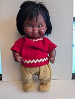 Front view of 10" Regal Canada Indigenous doll with red top and tan pants
