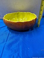 Side profile of ceramic bowl showing bark-like exterior texture and yellow interior, ruler for height scale